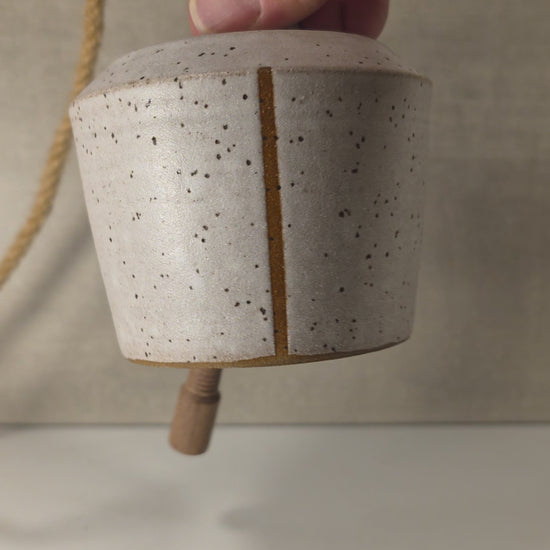 ringing of small handmade ceramic bell with stripe, glazed in a matte white speckled finish